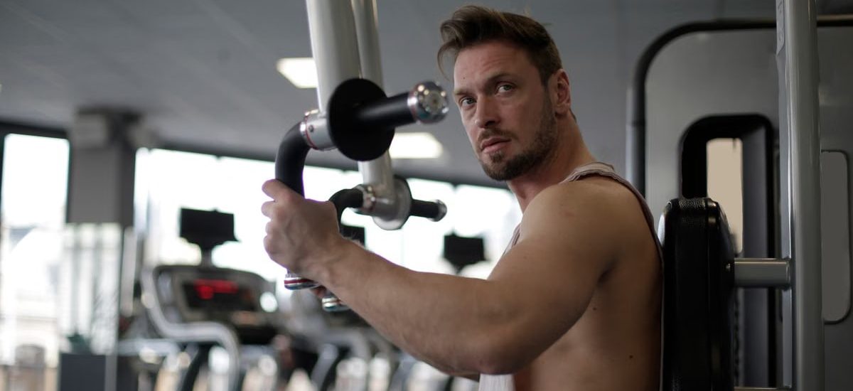 Focused man working out in a gym, showcasing biceps and determination.